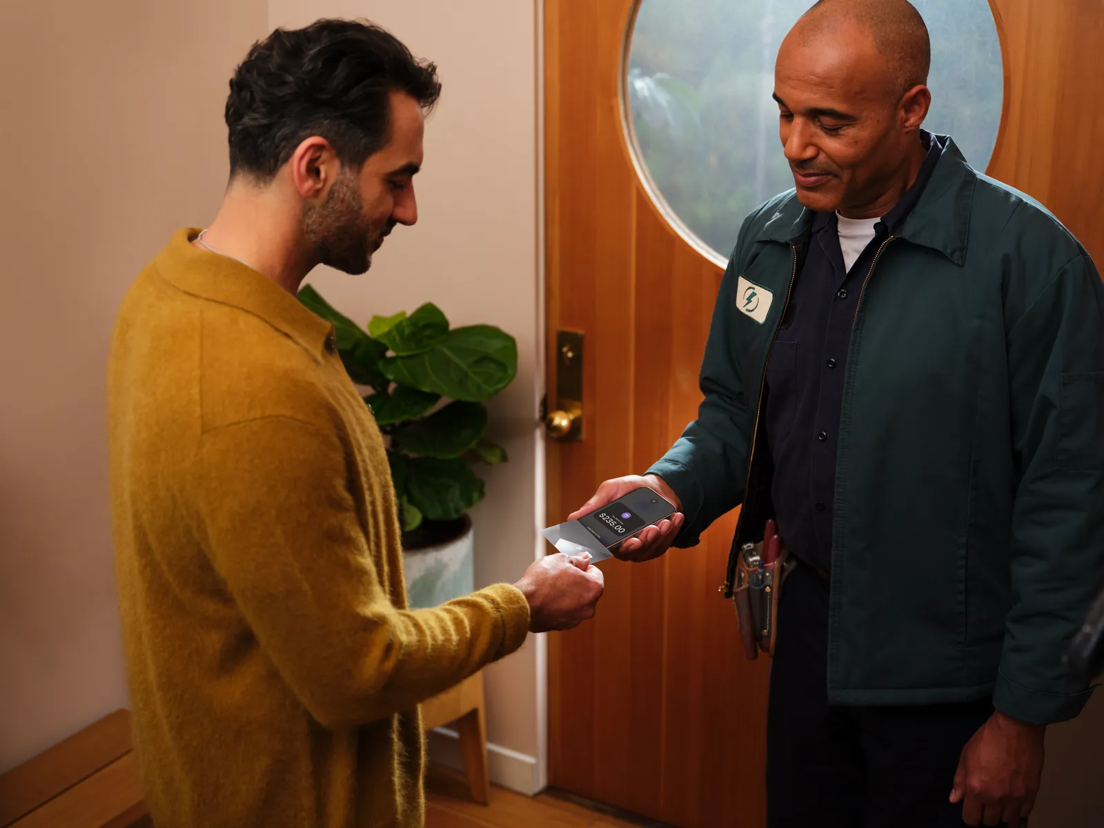 An electrician at a client's front door accepts a card payment with Tap to Pay on iPhone